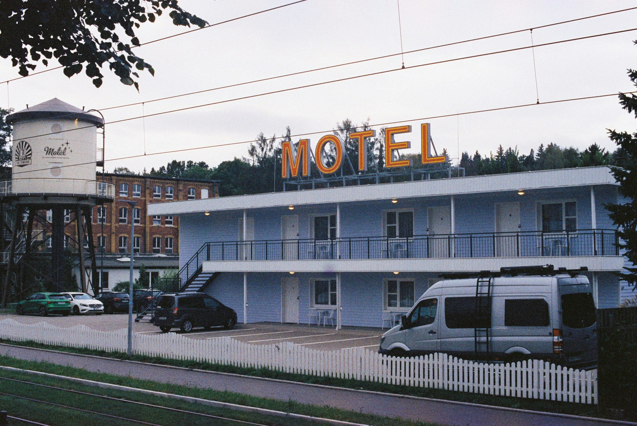 A quiet roadside motel exterior with cars parked outside.