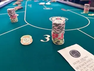 Stacks of pink, black, red, and cream poker chips on a green felt table at Casino Espinho with a Solverde Four Seasons poker slip in the corner
