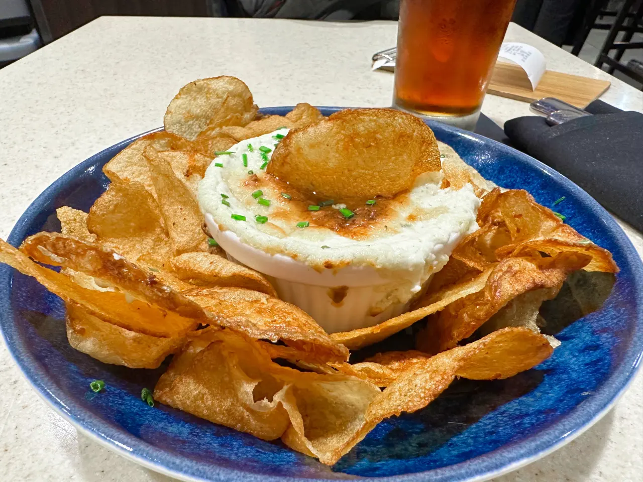 Photo of some potato chips with dip and a beer