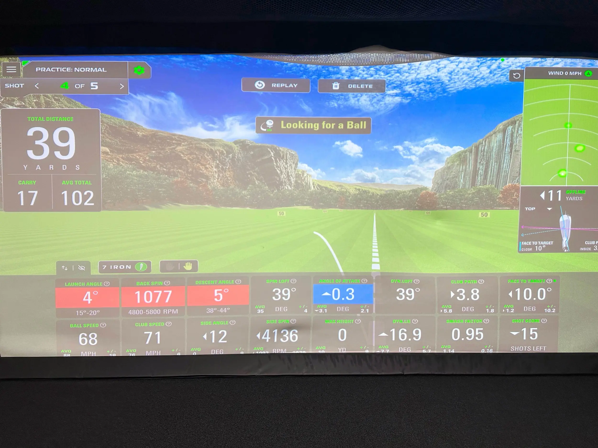 Indoor GOLFTEC simulator bay showing a practice screen with a canyon fairway background, 7 iron selected, total distance 39 yards, and swing metrics including launch angle, back spin, club path, and face to target.