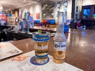 A Corona Light bottle and a lime-garnished beer in a Ru Ru's glass on the bar at Ru Ru's Tacos & Tequila