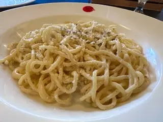 A plate of cacio e pepe at Sergio Crivelli in Matosinhos with black pepper and grated cheese on a wide white bowl