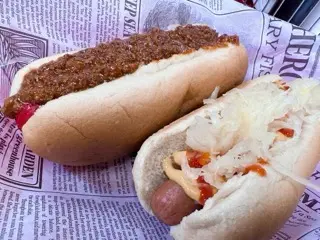 Two hot dogs from Skeeter's in Wytheville on branded paper, one covered in dark chili and one topped with kraut, mustard, and ketchup
