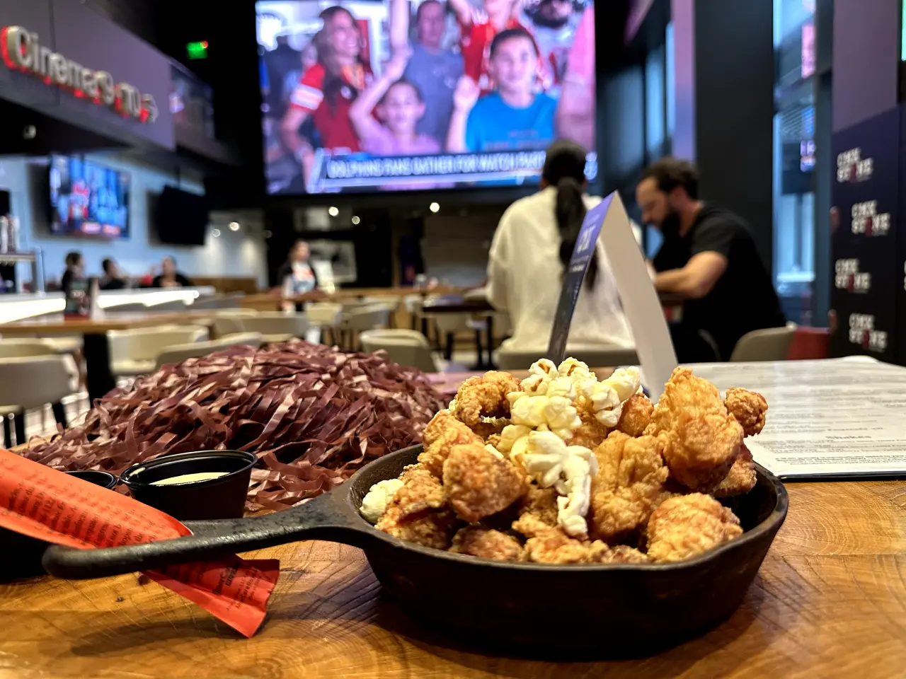 Photo of popcorn, chicken and a large tv with football