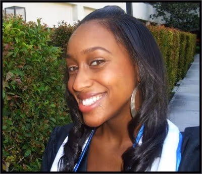 Mitrice Richardson smiling outdoors, wearing a graduation stole